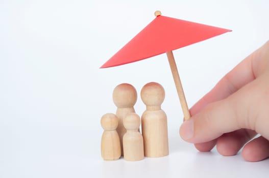 Family wooden dolls covered with toy umbrella with customizable space for text. Copy space concept.