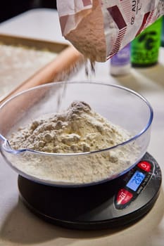 Precision in the kitchen, 768 grams of flour pour into a glass bowl on a digital scale for homemade pasta in Indiana.