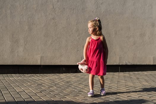 Child girl walks and have fun outdoor with cochlear implant on the head. Hearing aid and treatment concept. Copy space vertical.