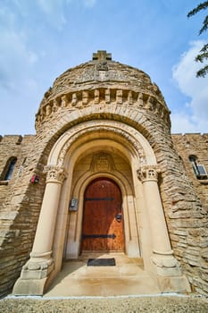 Gothic grandeur of Bishop Simon Brute College entrance, showcasing historical architecture and Christian heritage under a spring sky.