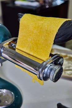 Fresh homemade pasta rolling through a machine in a Fort Wayne kitchen, demonstrating culinary craftsmanship and food safety.
