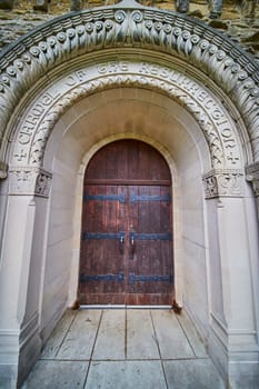 Spring day at Bishop Simon Brute College, showcasing the grandeur of Gothic architecture and Christian symbolism on a historic church door.