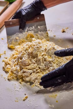 Skilled hands in black gloves knead homemade pasta dough in a bright, professional kitchen, Fort Wayne, Indiana