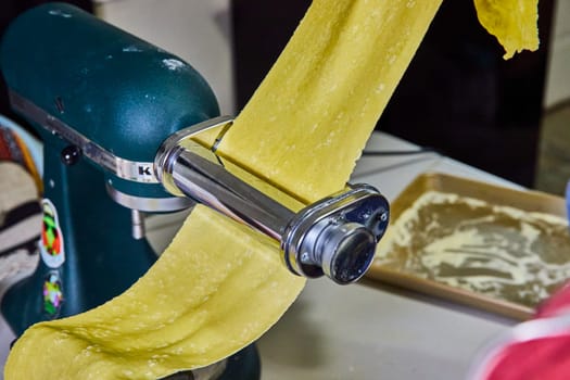 Freshly prepared pasta emerges from a vibrant green stand mixer in a cozy Indiana kitchen, demonstrating the charm of homemade Italian cooking.