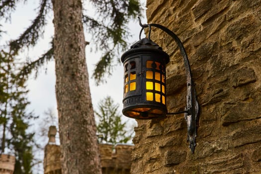 Vintage lantern on a stone wall at Bishop Simon Brute College, Indiana, casting a warm glow amidst a tranquil, rustic setting