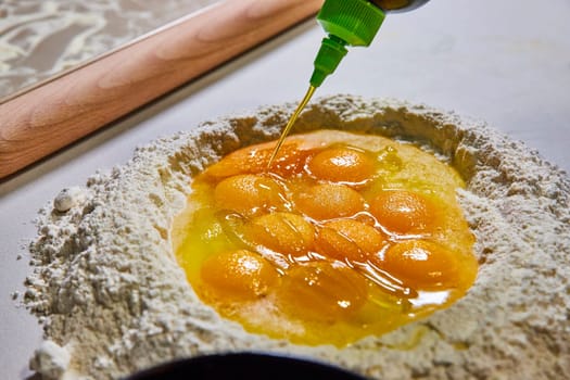 Fresh ingredients in a well of flour for homemade pasta, with a drizzle of olive oil, in a Fort Wayne kitchen