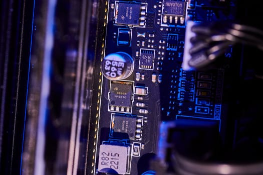 Close-up view of a high-tech computer motherboard bathed in cool blue light showcasing intricate electronic components. Macro image from Indiana, USA.