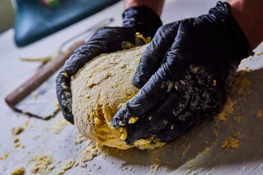 Expert hands kneading fresh pasta dough in a professional kitchen, capturing the essence of homemade cooking in Fort Wayne, Indiana.