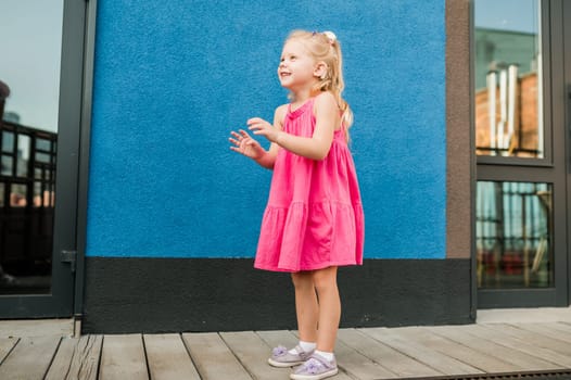 Child girl with hearing aids and cochlear implants having fun outdoor speak and playing. Copy space and empty place for advertising.