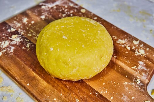 Freshly kneaded vibrant yellow dough on a rustic wooden board, evoking the warmth of home baking in Fort Wayne, Indiana.