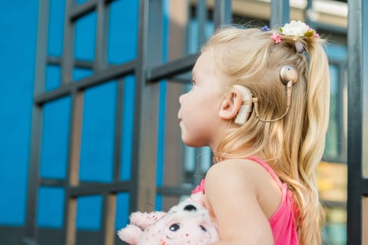 Child walks with cochlear implant system. Installation cochlear implant on child girl ear for restores hearing. Kid hears after hear return to normal. Diversity inclusion