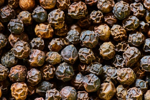 Macro shot of richly textured black peppercorns densely packed, showcasing earthy tones and organic form, perfect for culinary and global cuisine concepts.