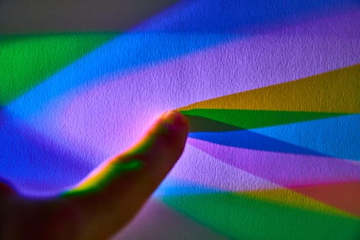 Exploring Light Refraction - A Close-up of a Human Finger Pointing at a Vivid Rainbow Gradient in Indiana