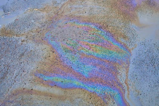 Textured stain of fuel or oil on wet asphalt on a rainy day.