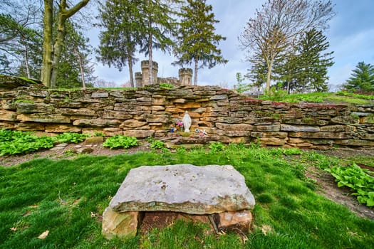 Serene Spring morning at Bishop Simon Brute College, featuring a rustic stone wall with floral alcove in a tranquil garden setting