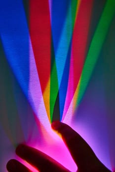 Exploring Color Theory: A hand interacts with a vibrant rainbow light spectrum in an abstract, indoor setting in Fort Wayne, Indiana.