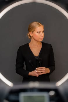 A woman in a black suit holding makeup brushes. Concept of professionalism and sophistication