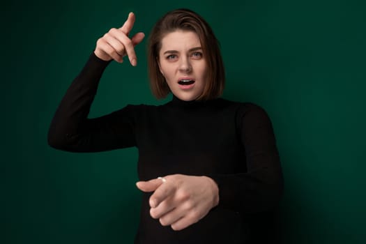 A woman wearing a black shirt is pointing at something in the distance, her arm extended and finger outstretched. She appears focused and determined as she gestures towards the unseen object.