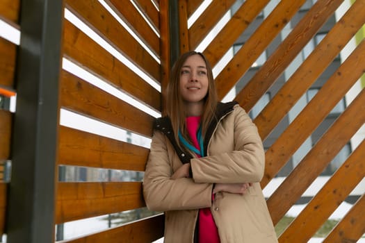 A woman standing confidently in front of a rustic wooden structure, looking towards the camera with a determined expression. She is wearing casual attire and the structure behind her is weathered and textured.