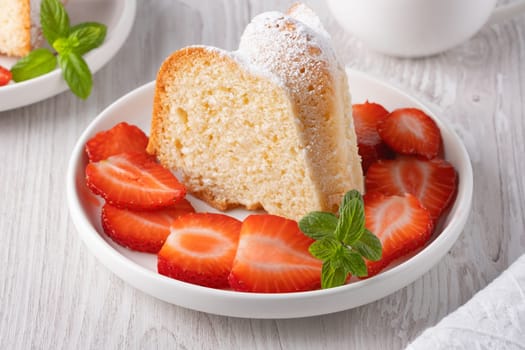 Piece of cupcake with strawberries on a plate.