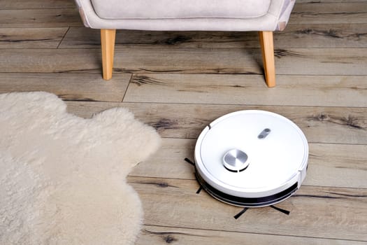 A robot vacuum cleaner on a wooden floor. Technologies for home cleaning. Selective focus.