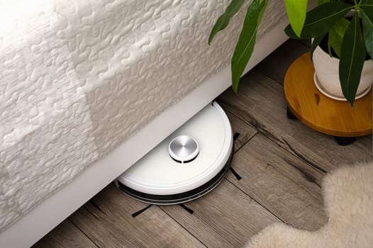 A robot vacuum cleaner on a wooden floor. Technologies for home cleaning. Selective focus.
