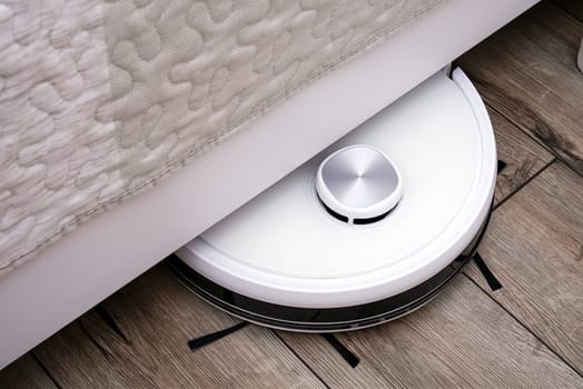 A robot vacuum cleaner on a wooden floor. Technologies for home cleaning. Selective focus.