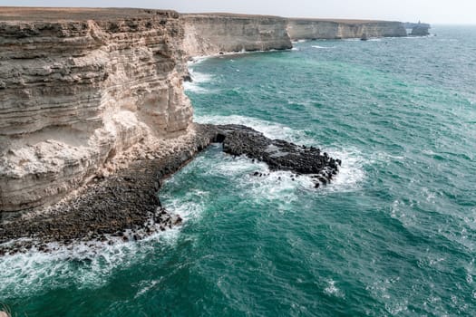 The ocean is calm and the shoreline is rocky. The water is a deep blue color. The rocks are jagged and the waves are small. The scene is peaceful and serene