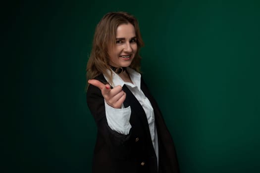 A woman dressed in a suit is standing in a confident posture, pointing directly at the camera with a serious expression on her face. She exudes authority and assertiveness in this corporate setting.
