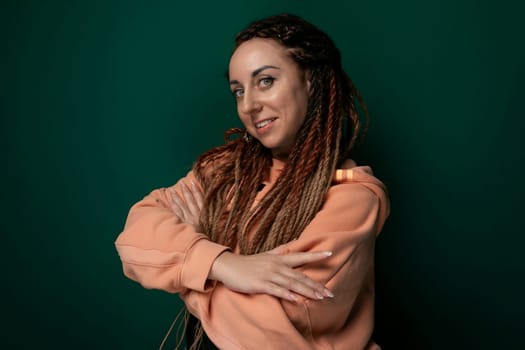 A woman with dreadlocks stands with her arms crossed in a confident pose. She appears determined and assertive, exuding a strong presence and a sense of self-assurance.