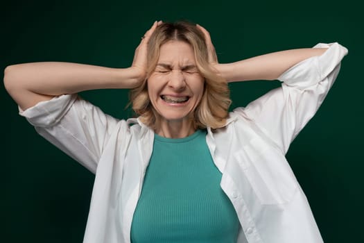 A woman standing with her hands on her head, displaying a gesture of distress or frustration. She appears to be in a state of worry or concern.