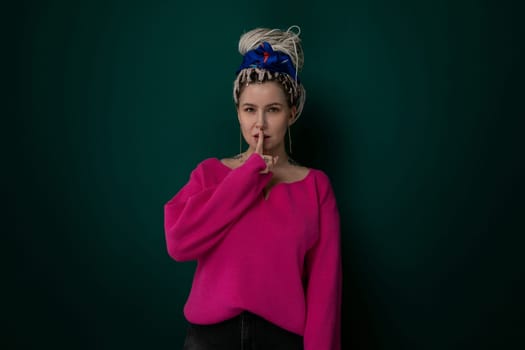 A woman wearing a pink sweater is striking a pose for a photograph. She appears confident and poised, focusing on the camera in front of her. The background is neutral, allowing the woman to stand out in her vibrant attire.