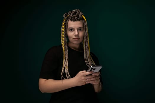 A woman with dreadlocks is holding a tablet in her hand, looking at the screen with focused concentration. Her facial expression conveys deep intent, possibly engaging with digital content or work-related tasks.