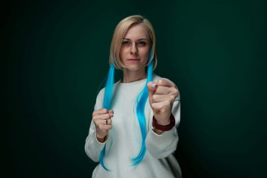 A woman with striking long blue hair is seen in the image, holding a pair of scissors in her hands. She appears focused on her task, perhaps preparing to cut her own hair or performing a creative haircut.
