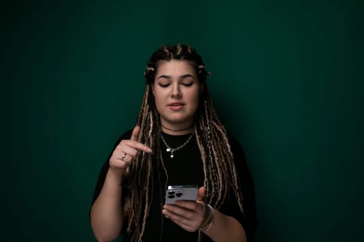 A woman with dreadlocks is seen looking intently at her cell phone screen, engrossed in whatever is displayed. Her hair is styled in intricate dreadlocks, and her focus is solely on the device in her hands.