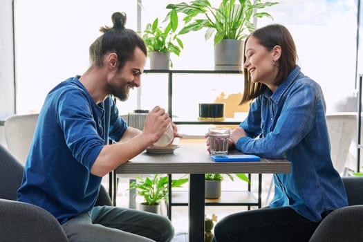 Laughing rejoicing cheerful young couple sitting together at table in cafe. Joyful emotions, enjoyment, friendship, happiness, love, togetherness, lifestyle relationships communication youth concept