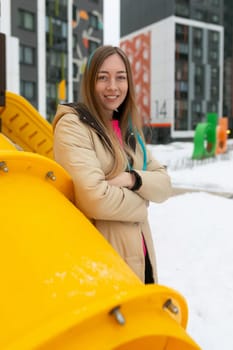 A woman is standing in front of a bright yellow object. She appears contemplative, looking towards the object. The scene is simple yet striking, with the contrast between the woman and the vibrant yellow catching the eye.