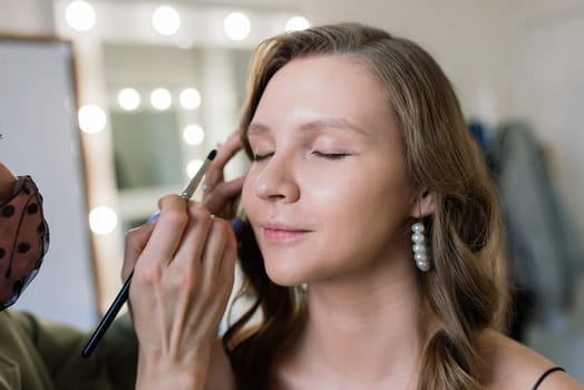 Woman make-up artist work in a studio with model