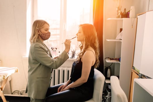 Woman make-up artist work in a studio with model