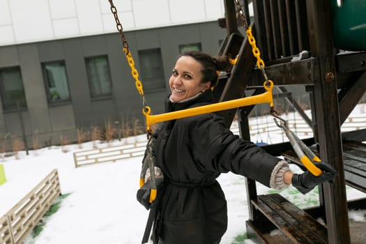 Lifestyle concept, carefree brunette woman in a black winter jacket walking on the playground.