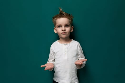 A young male child is shown standing in front of a vibrant green wall, looking directly at the viewer. He appears curious and engaged, with a neutral expression.