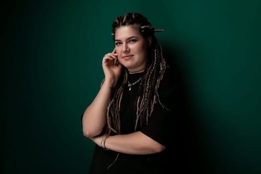 A woman with dreadlocks is engaged in a phone conversation, her phone pressed to her ear as she speaks. Her facial expression suggests concentration and focus as she communicates with the person on the other end of the call.