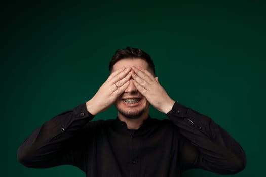 A man is shown with both hands covering his eyes. He appears to be shielding his eyes from something or expressing distress.