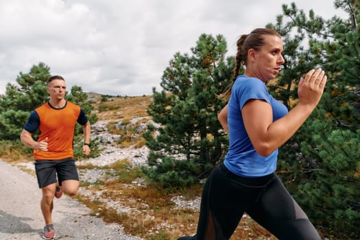 A couple dressed in sportswear runs along a scenic road during an early morning workout, enjoying the fresh air and maintaining a healthy lifestyle.