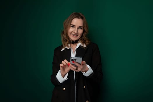 A woman is holding a smart phone in her hands, looking at the screen intently. Her fingers are tapping on the device, indicating she is interacting with it.