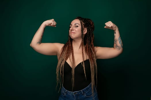 A woman with dreadlocks is confidently striking a pose while someone is taking her picture. She is exuding a sense of style and self-assurance in her posture and expression.