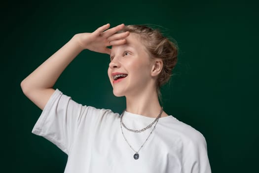 A woman is depicted wearing a white shirt and a necklace in this straightforward image. She stands confidently, showcasing her elegant attire and accessories.