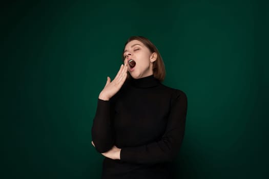 A woman wearing a black shirt is shown with her mouth open. She is holding her mouth wide with her hand in a gesture of surprise or shock.