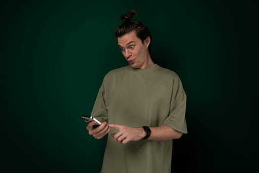 A man is seen holding a cell phone in his hand. The phone is positioned in his palm while his fingers grip the edges. He appears focused on the screen, possibly texting or browsing.