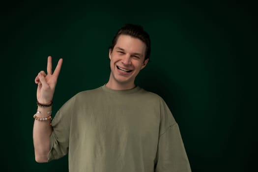 A man is extending his two fingers in a V shape, forming a peace sign gesture. He is holding his hand up towards the camera, with a neutral expression on his face.
